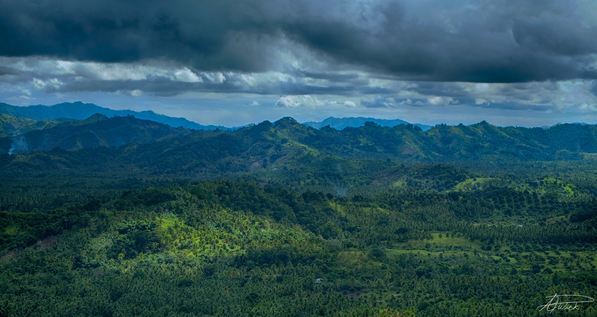 Layered blue Philippine mountains rolling toward the horizon under a heavy storm sky