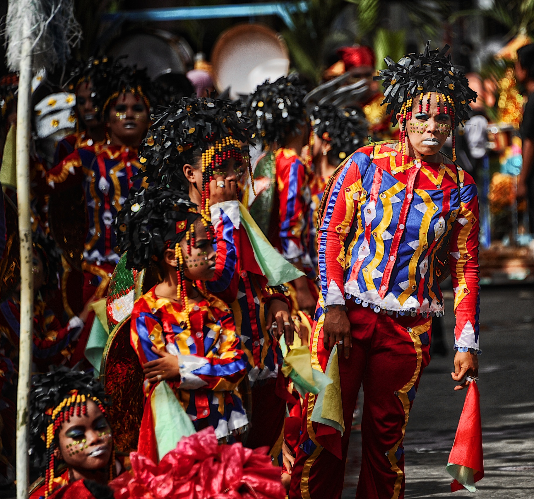 Ati-Atihan troupe in red, blue and yellow striped costumes marching through the street