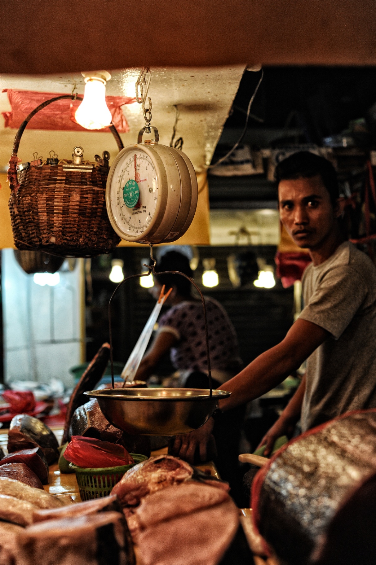 Vendor with hanging market scale at a Philippine wet market